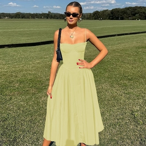 Detail of light yellow summer dress with corset waist and flowy hemline on green grass