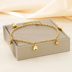 Détail d'une chevillère à billes dorées avec cinq clochettes sur un coffret à bijoux