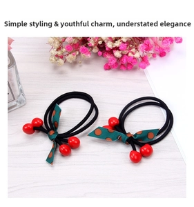 Close-up of cherry hair ties with red beads and green polka dot bow ribbons
