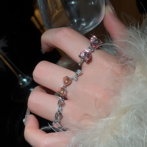 Close-up of sparkling heart-shaped pink zircon rings set with pavé stones on a model hand