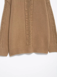 Dettaglio di un maglione a trecce color cammello con trame traforate e tessuto morbido