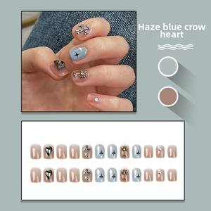 Close-up of handmade press-on nails with blue matte finish and metallic cross charms