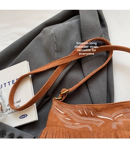 Close-up of brown suede bag with ethnic embroidery and elegant fringe tassels