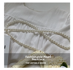 Close-up of elegant white pearl chain strap with metal hooks on a woven bag