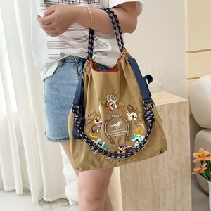 Detail of khaki nylon bag featuring intricate carousel embroidery and blue drawstring rope