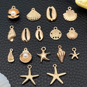 Macro shot of 14 gold shell and starfish alloy pendants with pearls for DIY jewelry