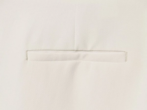 Vue macro détaillée de la poche horizontale et des coutures fines du blazer blanc cassé