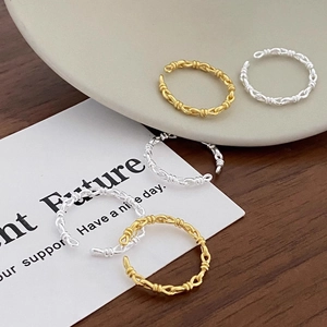 Macro detail of gold and silver braided rings on a ceramic plate with wood background