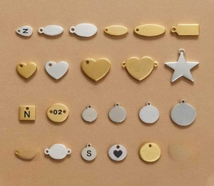 Macro shot of 18K gold and silver stainless steel pendants with engraved inspiring words
