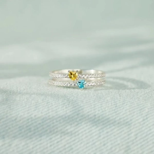 Elegant s925 silver double heart ring with blue and yellow zircons on textured blue fabric