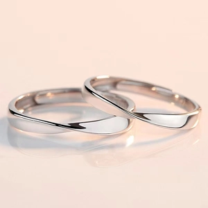 Close-up of silver Mobius couple rings on a pink reflective surface with clear reflections