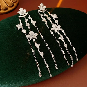 Detailed macro view of silver flower tassel earrings with zircons on green velvet