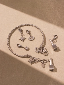 Detailansicht eines silbernen geflochtenen Armbands mit Stern- und Lippenanhängern