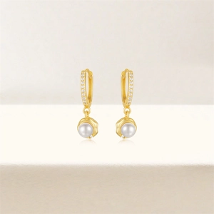 Close-up of golden 925 silver hoop earrings with zircon pavé and hanging white pearl