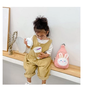Detailed view of pink rabbit canvas chest bag on a toddler wearing khaki overalls