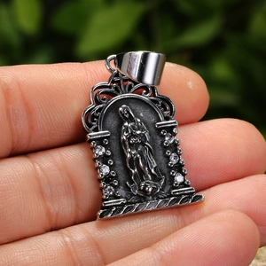 Silver angel religious pendant with inlaid crystals shown on hand against nature
