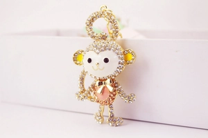 Macro shot of gold-plated monkey keychain with pink enamel and sparkling crystals