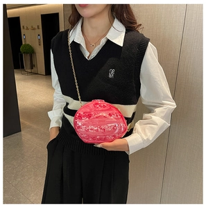 Chic pink shell-shaped acrylic evening bag with a gold chain strap worn by a model