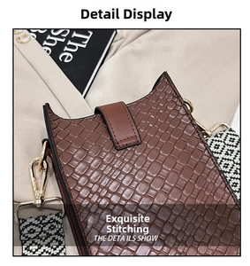 Detailansicht der braunen Kroko-Tasche mit Goldhaken und gewebtem Schultergurt