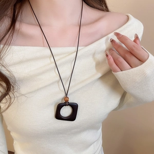 Detail of square resin pendant on brown wax cord necklace worn by model