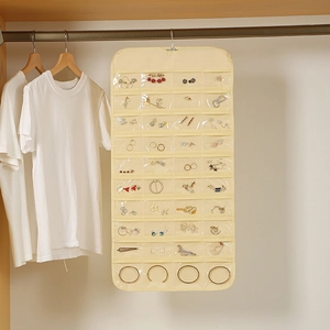 Beige double-sided 80-pocket jewelry organizer hanging in a closet for necklaces