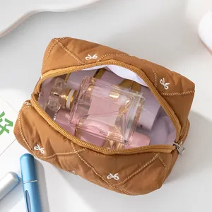 Spacious brown quilted cosmetic bag with white bow embroidery and gold zipper closure