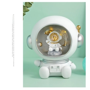 Macro view of astronaut crystal ball music box with warm LED lighting and resin base