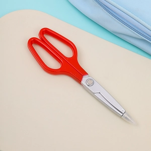 Close-up of portable red scissors with sharp silver metal blades and clear safety cap