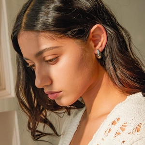 Close-up of model wearing polished silver teardrop earrings with a metallic finish