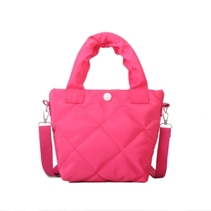 Magenta quilted tote bag with diamond stitching and ruffled handle on white background