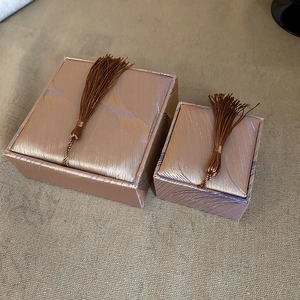 Detail of two rose gold jewelry boxes with fabric texture and decorative tassels