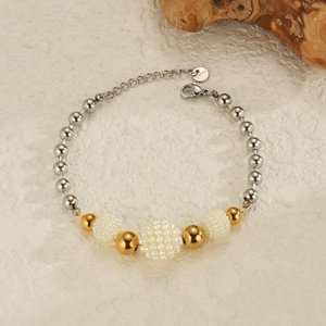 Minimalist mixed metal beaded bracelet with gold and silver accents on stone background