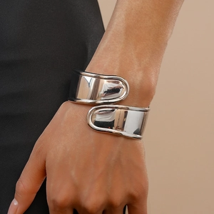 Close-up of a wide silver irregular cross wrap cuff bracelet with a mirror-polished finish