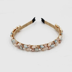 Detailed view of gold headband with pink and blue crystals and woven gold thread