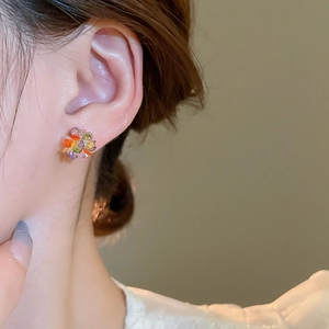 Detail of colorful floral crystal stud earring worn on model featuring vibrant gemstones