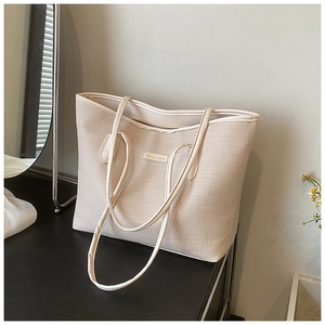 Close-up of beige woven tote bag with Fashion & Bags label on a dark table surface