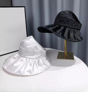 Detail of elegant wavy-brim sun visors with sparkling rhinestones in black and white