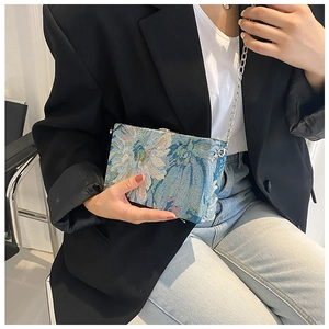 Detail of floral jacquard texture on blue chain crossbody bag with silver hardware