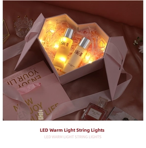 Detail of warm yellow LED string lights inside a pink heart-shaped gift box for decoration