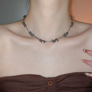 Detail of silver metallic beaded necklace with minimalist industrial design on model neck
