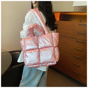 Pink metallic quilted puffer tote bag with padded shoulder strap shown on a model