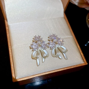 Detailed close-up of 14k gold plated flower stud earrings with zircon and pearl bow