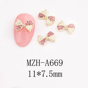 Macro view of gold bow-knot nail art charms with pink rhinestones for DIY decoration