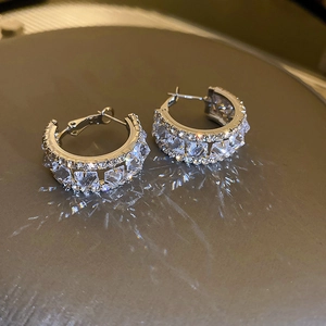 Macro view of C-shaped hoop earrings featuring double-row inlaid cubic zirconia stones