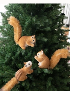 Close-up of three cute squirrel ornaments with sisal tails on a green Christmas tree