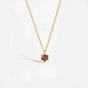 Macro detail of fine gold chain with round purple zircon pendant on white background