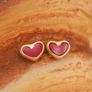 Boucles d'oreilles cœur dorées classiques avec émail rouge sur fond chaleureux