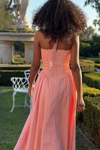 Detail of pink floral halter dress showing open back design and flowing skirt in a garden