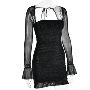 Detail of black sequined dress showing sheer mesh long sleeves and flared cuffs design
