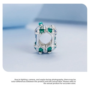 Detail of 925 silver suitcase charm with deep green and blue enamel star patterns